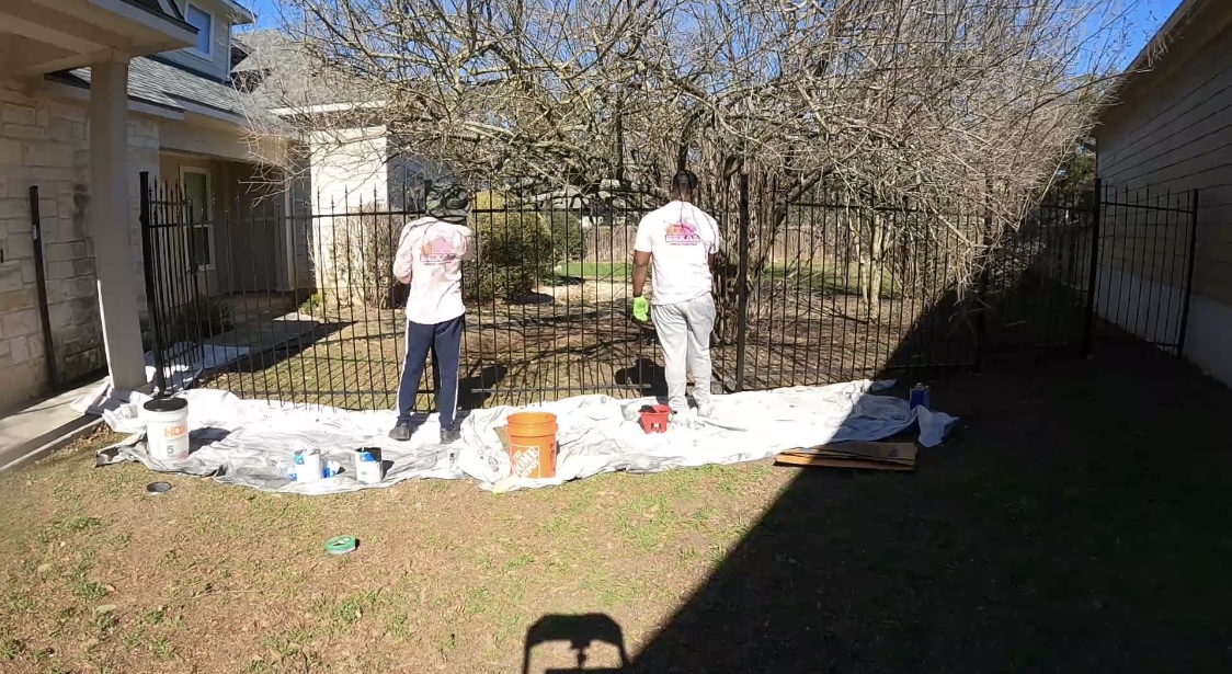 Bexar Fence Painting employees painting and staining a wrought iron fence in San Antonio, TX.